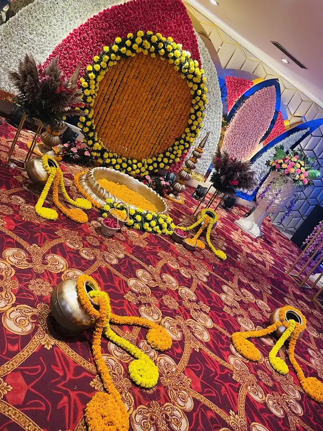 A row of round tables with peach and gold linens under an open-sided tent, maroon drapes and a buffet counter along one side.